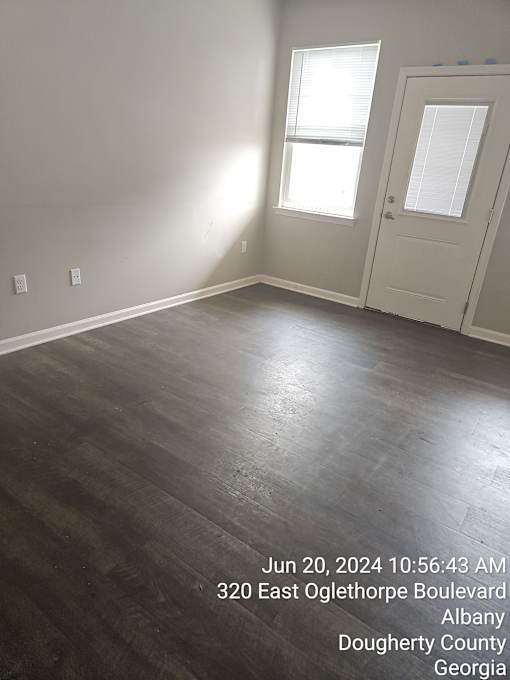 A room with a wooden floor and a door on the right side.