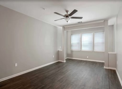 A room with a ceiling fan and a window with blinds.