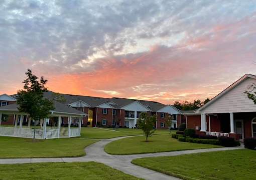 A sunset view of a residential area with houses and a pathway.