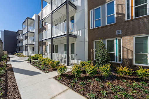 A modern apartment complex with a walkway and landscaping.