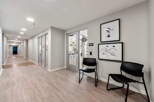 A hallway with two chairs and pictures on the wall.