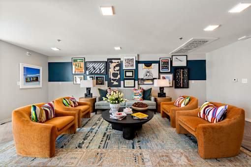 A room with a round table and orange chairs.