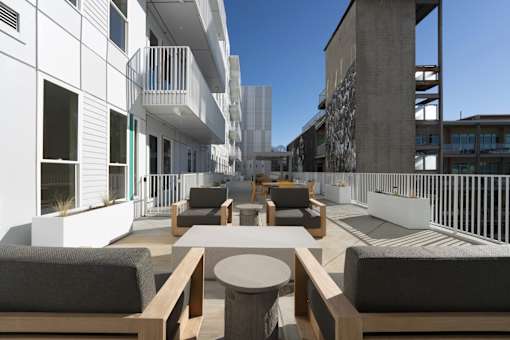 A modern outdoor seating area with white walls and wooden furniture.