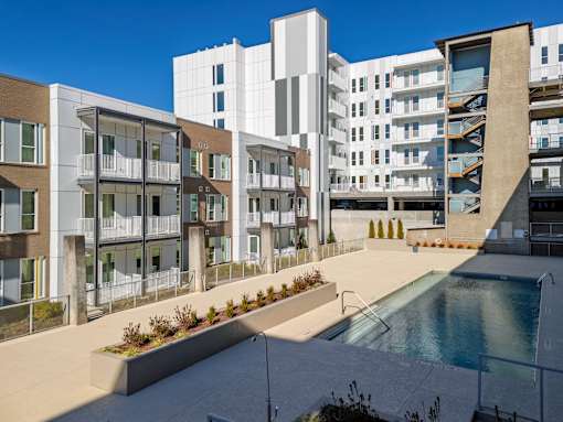 A modern apartment complex with a pool in the foreground.