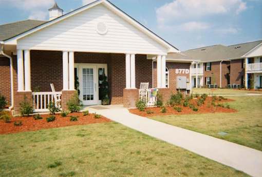 A white house with a brick facade and a porch with white railings.