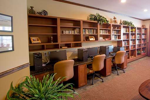 A room with a desk, chairs, and a bookshelf.