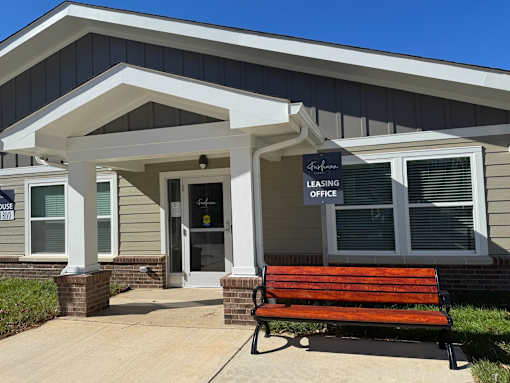 A bench is in front of a leasing office.