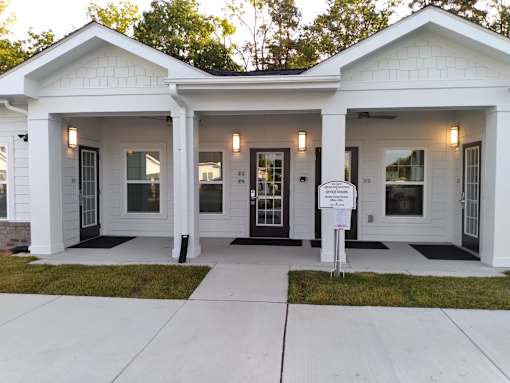 A white house with a black front door and a sign in front.