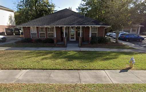 A small brick house with a porch and a fire hydrant in front.