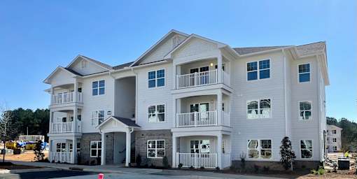 A large white residential building with multiple balconies and windows.