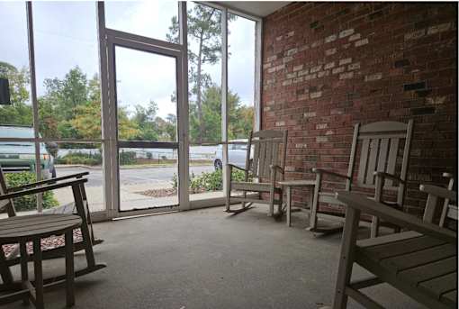 A room with a brick wall and wooden chairs.