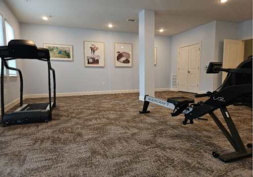 A room with a treadmill and a stationary bike.