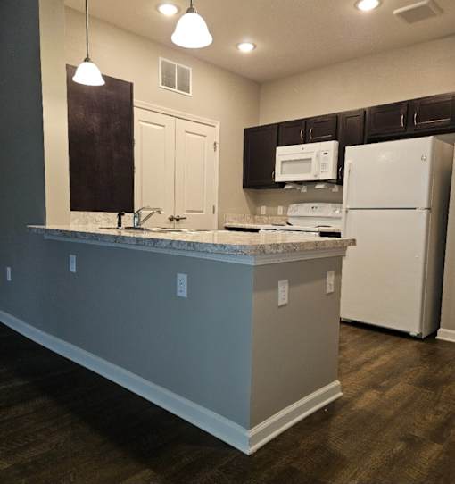 A kitchen with a white refrigerator and a counter with a sink.