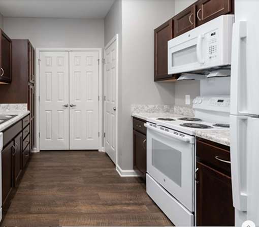 A kitchen with white appliances and brown cabinets.