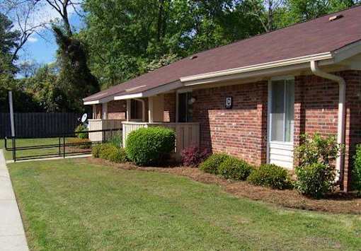 A brick house with a white door and a small garden in front.