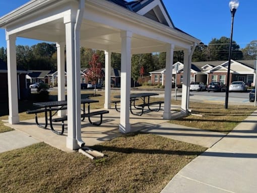 A white covered picnic area in front of a house.