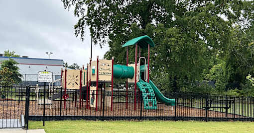 A playground with a green slide and a red and white structure.