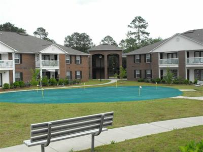 A bench is in front of a pool in a grassy area.