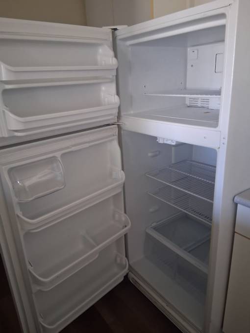 Two white refrigerators, one with the door open.