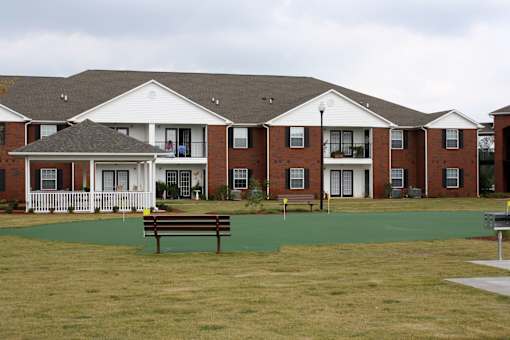 A large building with a white porch and a brown bench in front of it.