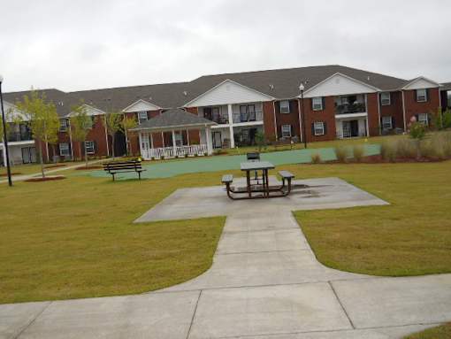 A large building with a red brick exterior and a green lawn in front.