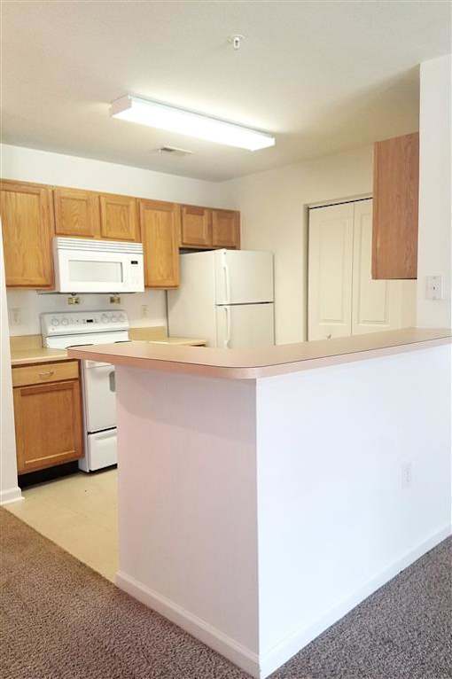A kitchen with white appliances and wooden cabinets.