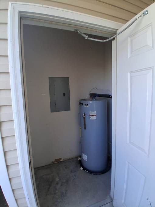 A small room with a water heater and a door.