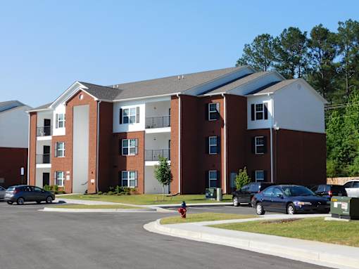 A large apartment complex with cars parked in front.