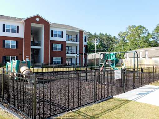 A playground with a black fence and a red brick building in the background.