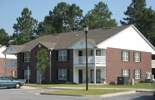 A street view of a residential area with apartment buildings and a car parked on the side of the road.