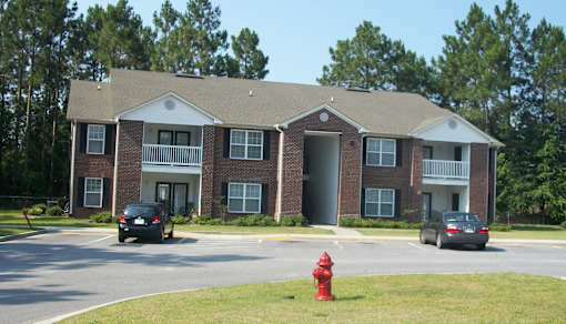 A red fire hydrant is in front of a brick apartment building.
