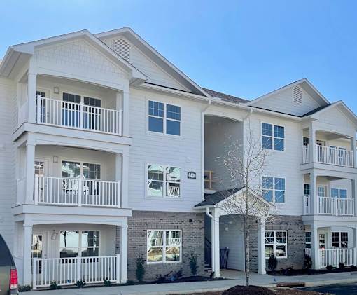 A white two-story residential building with balconies and a garage door.