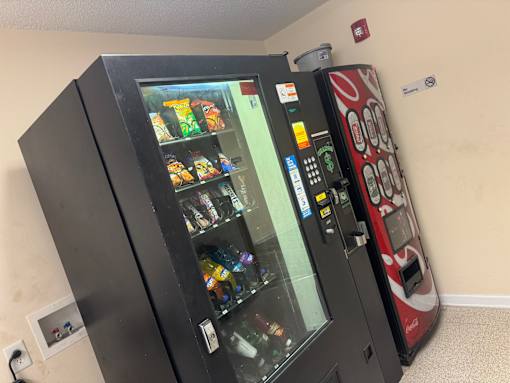 A black vending machine with a red and white one next to it.