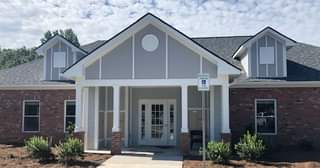 A white building with a black roof and a covered walkway.