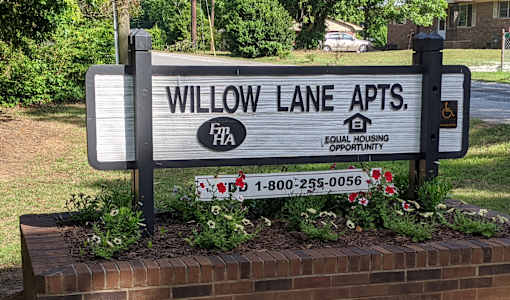 A sign for Willow Lane Apts with a phone number on it.