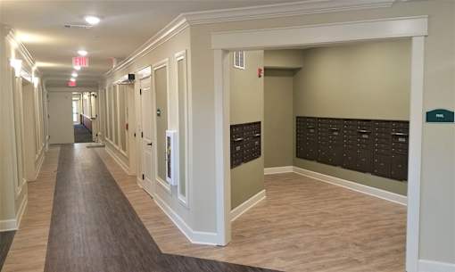 A long hallway with doors on the side and a red exit sign above.