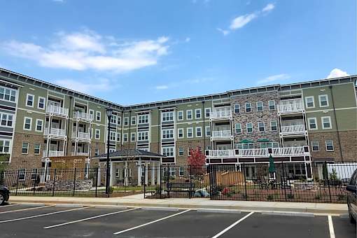 A large apartment complex with a parking lot in front.