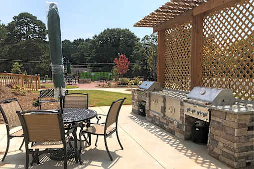 A patio with a table and chairs and a grill.