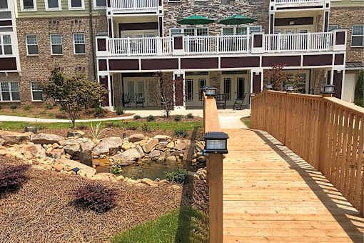 A wooden walkway leads to a building with a balcony.