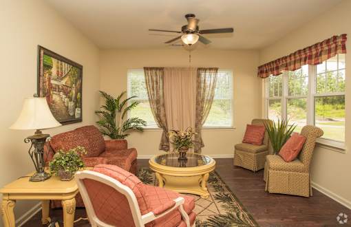 A living room with a yellow coffee table and red chairs.