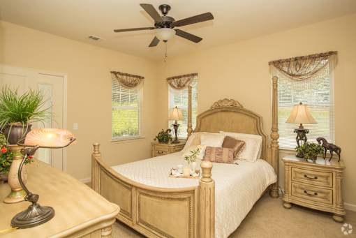 A bedroom with a large bed, a dresser, and a ceiling fan.