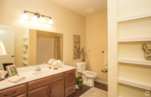 A bathroom with a toilet, sink, and mirror.