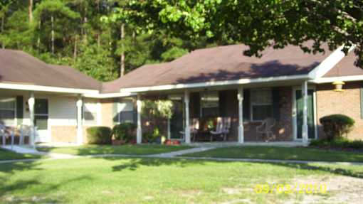 A house with a brown roof and white walls with a lawn in front.