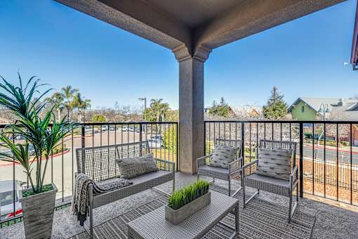 A balcony with a bench, cushions, and a potted plant.