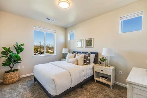 A bedroom with a large bed, nightstand, and a plant.