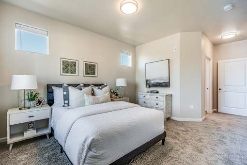 A bedroom with a large bed, nightstand, and a painting on the wall.