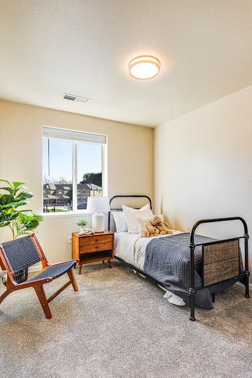 A bedroom with a bed, chair, and window.