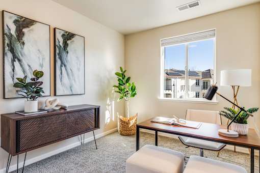 A room with a table, chairs, and two framed pictures on the wall.