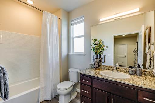 A white toilet sits in a bathroom with a white shower curtain.