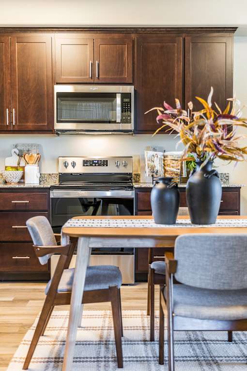 A kitchen with a table and chairs and a microwave above the stove.
